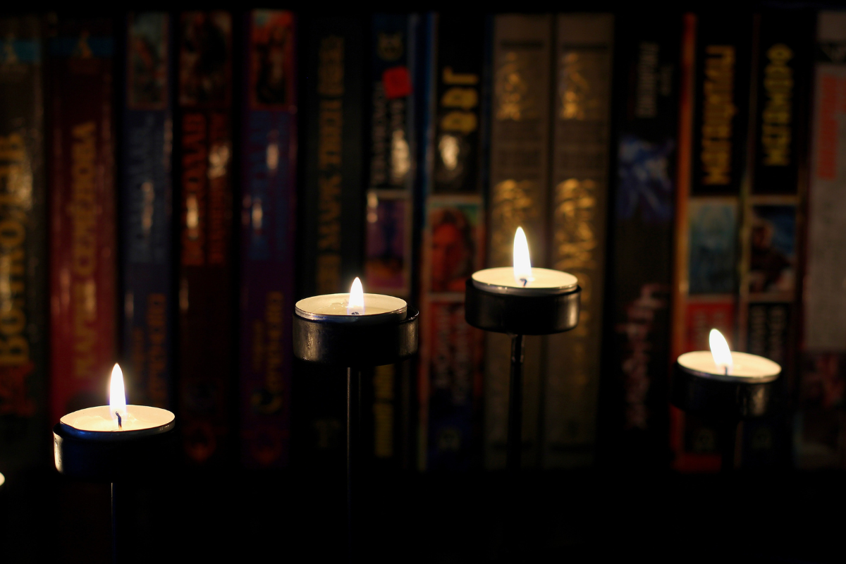 Dark bookshelf illuminated by candles.